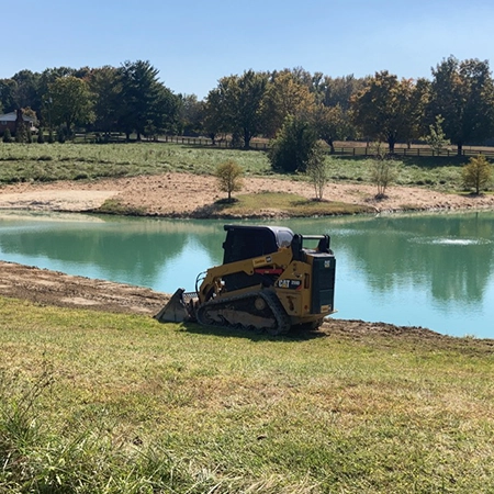 Small front end loader constructing a pond