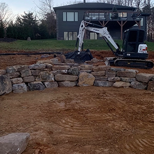 Bob Cat Front End Loader working on a stone wall